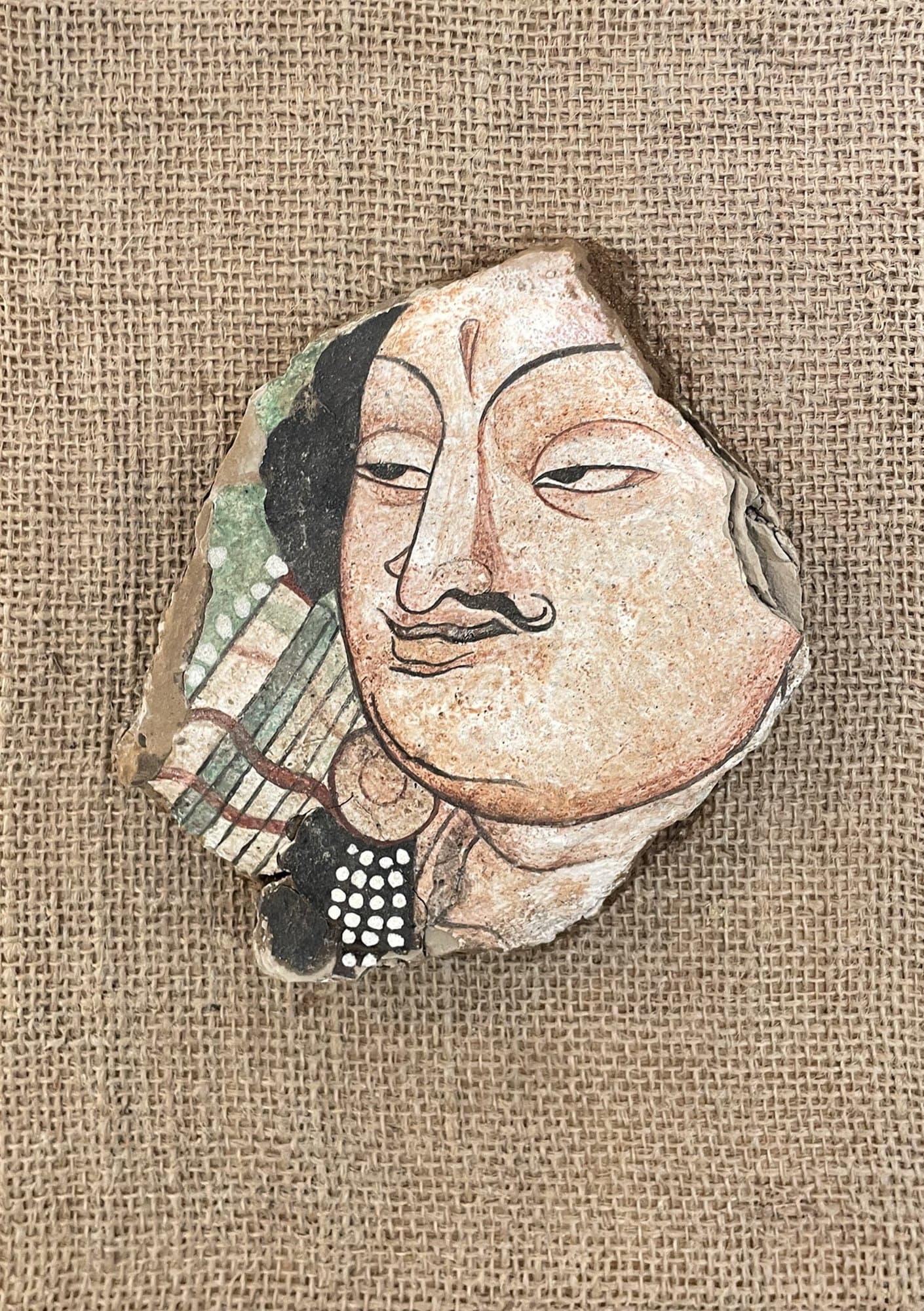 The Roman Merchant EN SEO Title: The Roman Merchant – Silk Road Mural on Mud-block, Jiadong Yan Meta Description: A merchant’s face painted on a natural mud-block fragment in mineral pigments and Chinese ink, drawing on ancient Silk Road cave murals. By Jiadong Yan, 20×20 cm, 2024. URL Slug: jiadong-yan-roman-merchant-mud-block-mural Keywords: Silk Road mural art, mud-block painting, cave mural replica, Jiadong Yan, mineral pigment art Alt Text: Irregular mud-block fragment painted with the face of a moustached merchant in a cave mural style, mounted on burlap TH SEO Title: The Roman Merchant จิตรกรรมฝาผนังบนก้อนดิน โดยเจียต้ง หยาน Meta Description: ใบหน้าพ่อค้าวาดบนก้อนดินธรรมชาติด้วยสีแร่และหมึกจีน ได้แรงบันดาลใจจากจิตรกรรมฝาผนังถ้ำโบราณบนเส้นทางสายไหม โดยเจียต้ง หยาน 20×20 ซม. ปี 2024 Keywords: จิตรกรรมฝาผนังสายไหม, ภาพวาดบนก้อนดิน, จิตรกรรมถ้ำโบราณ, เจียต้ง หยาน, งานศิลปะสีแร่ Alt Text: เศษก้อนดินทรงอิสระวาดใบหน้าพ่อค้าไว้หนวดในสไตล์จิตรกรรมฝาผนังถ้ำ ติดบนผ้ากระสอบ