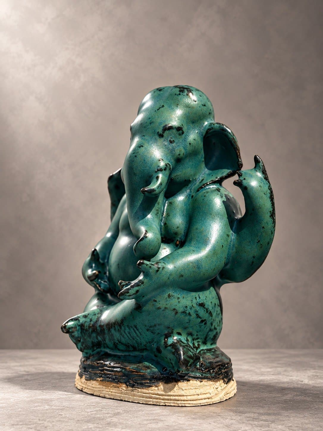 ชื่อ: Untitled * SEO Title (EN): Untitled – Ceramic Sculpture by Watcharin Chumek * SEO Title (TH): Untitled – ประติมากรรมเซรามิก วัชรินทร์ ชูเมฆ * Meta Description (EN): A seated four-armed Ganesha in speckled jade-green glaze, softly rounded yet anatomically assured. An original devotional sculpture by Thai sculptor Watcharin Chumek. * Meta Description (TH): พระพิฆเนศประทับนั่ง สี่กร เคลือบสีเขียวหยกลายจุด รูปทรงอ่อนช้อยแต่มั่นคงด้วยความเข้าใจกายวิภาค ประติมากรรมรูปเคารพต้นฉบับร่วมสมัย โดยวัชรินทร์ ชูเมฆ * Alt Text (EN): Seated four-armed Ganesha ceramic sculpture in speckled jade-green glaze on a textured unglazed clay base * Alt Text (TH): ประติมากรรมเซรามิกพระพิฆเนศประทับนั่ง สี่กร เคลือบสีเขียวหยกลายจุดดำ บนฐานดินดิบผิวลายเส้น * URL slug: watcharin-chumek-jade-ganesha-sculpture * Keywords (EN): Ganesha sculpture, ceramic Ganesha, green Ganesha statue, contemporary Ganesha art, Thai devotional sculpture, original sculpture for sale * Keywords (TH): พระพิฆเนศ, องค์พระพิฆเนศเซรามิก, พระพิฆเนศสีเขียว, รูปเคารพร่วมสมัย, ประติมากรรมศิลปินไทย, บูชาพระพิฆเนศ