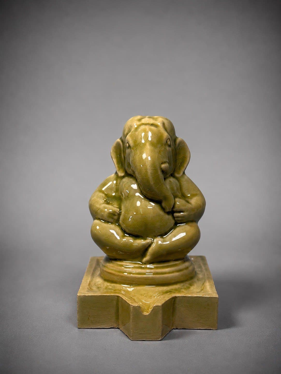 Ganesha – Celadon / พระพิฆเนศ เคลือบเซลาดอน SEO Title (EN): Celadon Ganesha – Crackle Glaze by Watcharin Chumek SEO Title (TH): พระพิฆเนศเคลือบเซลาดอนลายราน – วัชรินทร์ ชูเมฆ Meta Description (EN): A seated Ganesha in glossy olive celadon with fine crackle, echoing the ceramic heritage of Thailand. Original sculpture by Thai artist Watcharin Chumek. Meta Description (TH): พระพิฆเนศประทับนั่ง เคลือบเซลาดอนสีเขียวมะกอกเงางาม ผิวลายรานละเอียด สะท้อนมรดกงานเครื่องเคลือบไทย ผลงานต้นฉบับโดยวัชรินทร์ ชูเมฆ Alt Text (EN): Seated Ganesha sculpture in glossy olive-green celadon crackle glaze on a stepped pedestal with a spout Alt Text (TH): ประติมากรรมพระพิฆเนศประทับนั่ง เคลือบเซลาดอนสีเขียวมะกอกลายราน บนฐานย่อมุมมีรางน้ำ URL slug: watcharin-chumek-ganesha-celadon Keywords: celadon Ganesha, crackle glaze sculpture, Thai celadon, พระพิฆเนศเซลาดอน, เครื่องเคลือบลายราน