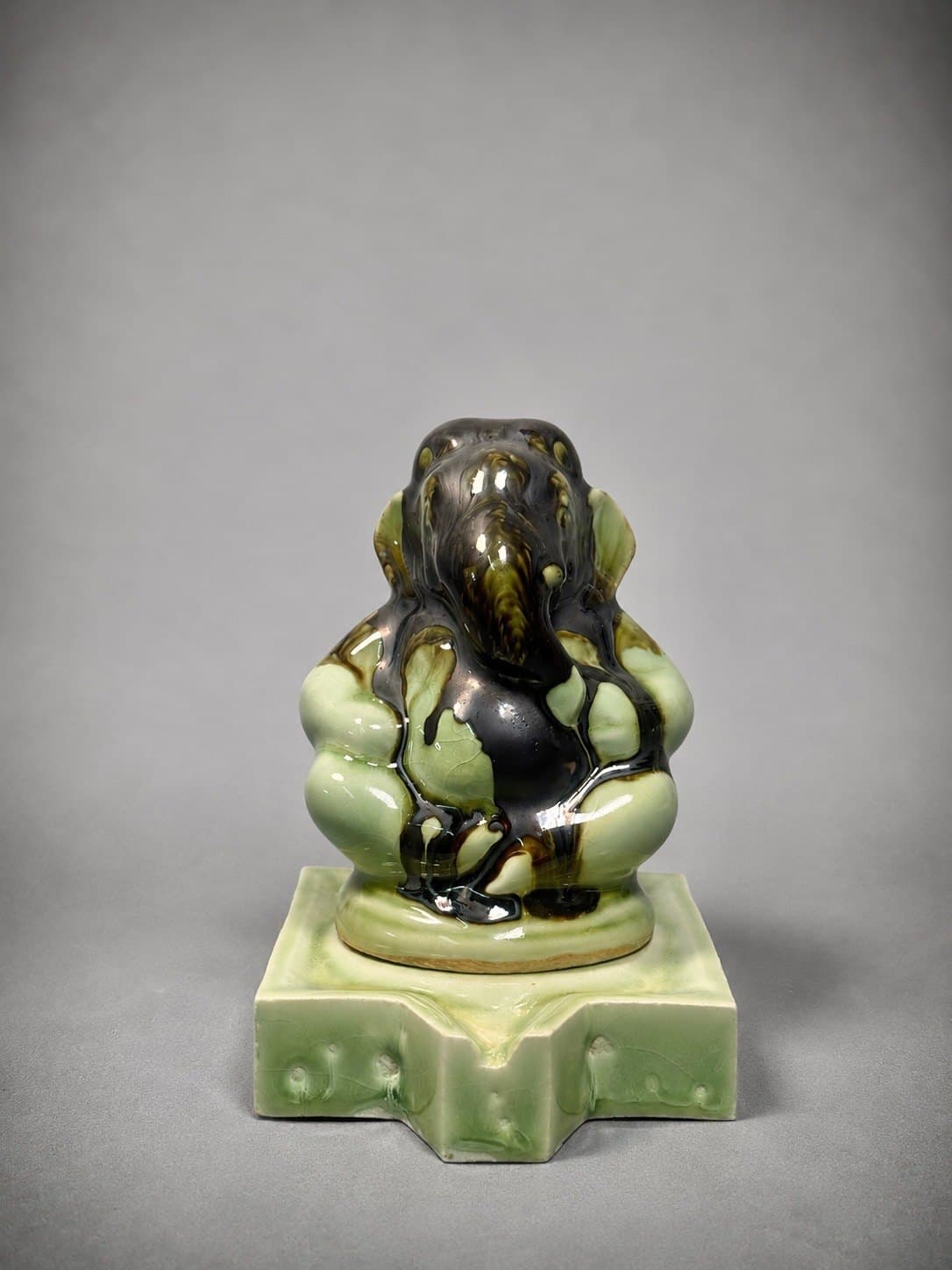 Ganesha – Celadon & Tenmoku Drip / พระพิฆเนศ เคลือบเซลาดอนไหลย้อย SEO Title (EN): Celadon Drip Glaze Ganesha – Watcharin Chumek SEO Title (TH): พระพิฆเนศเคลือบเซลาดอนไหลย้อย – วัชรินทร์ ชูเมฆ Meta Description (EN): A seated Ganesha in pale celadon green, flowed over with glossy dark brown glaze so no two pieces look the same. Original ceramic by Thai sculptor Watcharin Chumek. Meta Description (TH): พระพิฆเนศประทับนั่ง เคลือบเซลาดอนสีเขียวอ่อน ทับด้วยเคลือบสีน้ำตาลดำไหลย้อยเงางาม ลวดลายเกิดขึ้นเฉพาะชิ้น ไม่ซ้ำกัน ผลงานเซรามิกต้นฉบับ โดยวัชรินทร์ ชูเมฆ Alt Text (EN): Seated Ganesha ceramic sculpture in pale celadon green with dark brown drip glaze flowing over the head and body, on a stepped pedestal with a spout Alt Text (TH): ประติมากรรมเซรามิกพระพิฆเนศประทับนั่ง เคลือบเซลาดอนสีเขียวอ่อน มีเคลือบสีน้ำตาลดำไหลย้อยจากเศียรลงสู่องค์ บนฐานย่อมุมมีรางน้ำ URL slug: watcharin-chumek-ganesha-celadon-drip Keywords (EN): celadon Ganesha, drip glaze sculpture, tenmoku glaze, one-of-a-kind Ganesha, ceramic Ganesha statue Keywords (TH): พระพิฆเนศเซลาดอน, เคลือบไหลย้อย, พระพิฆเนศเซรามิก, พระพิฆเนศชิ้นเดียวในโลก